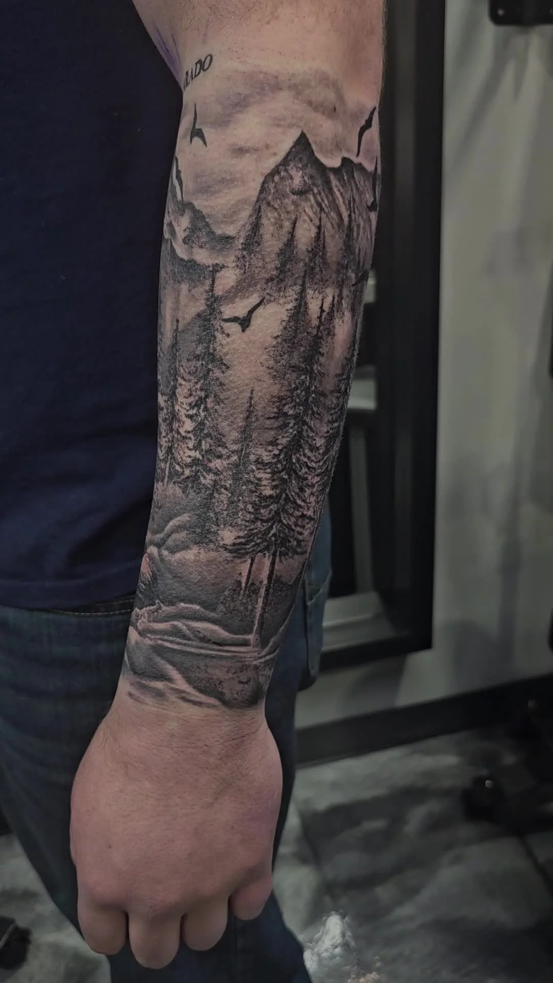 Mountain landscape with Colorado text and pine forest forearm tattoo by Alex Zamora